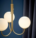 Trendig mssings lampa med tre vita glaskupor, lampan hnger i ett bltt rum